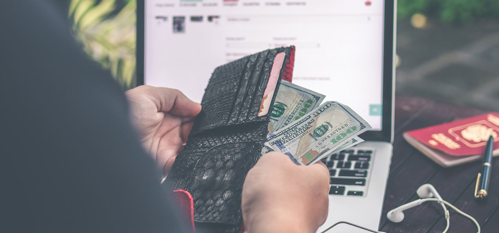 Person holding cash in front of laptop