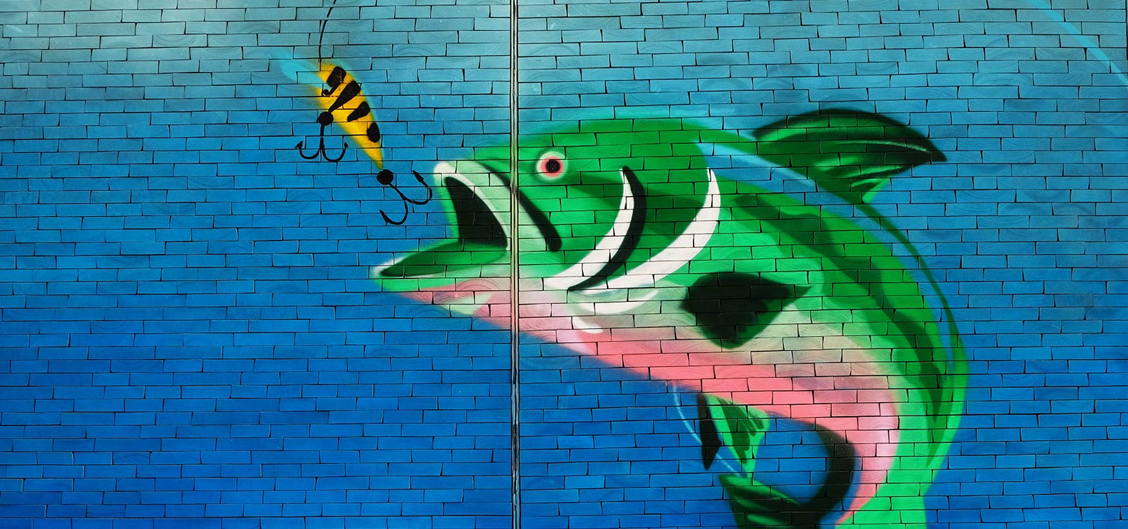 Fish about to eat a hook wall art on bricks