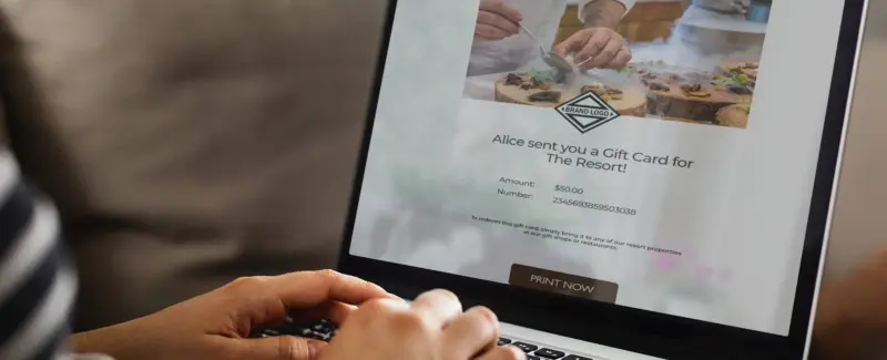 A customer using a laptop to view a personalized digital gift card delivered via the e-cards.io platform, illustrating the seamless, mobile-responsive recipient experience engineered by Seismic Pixels.